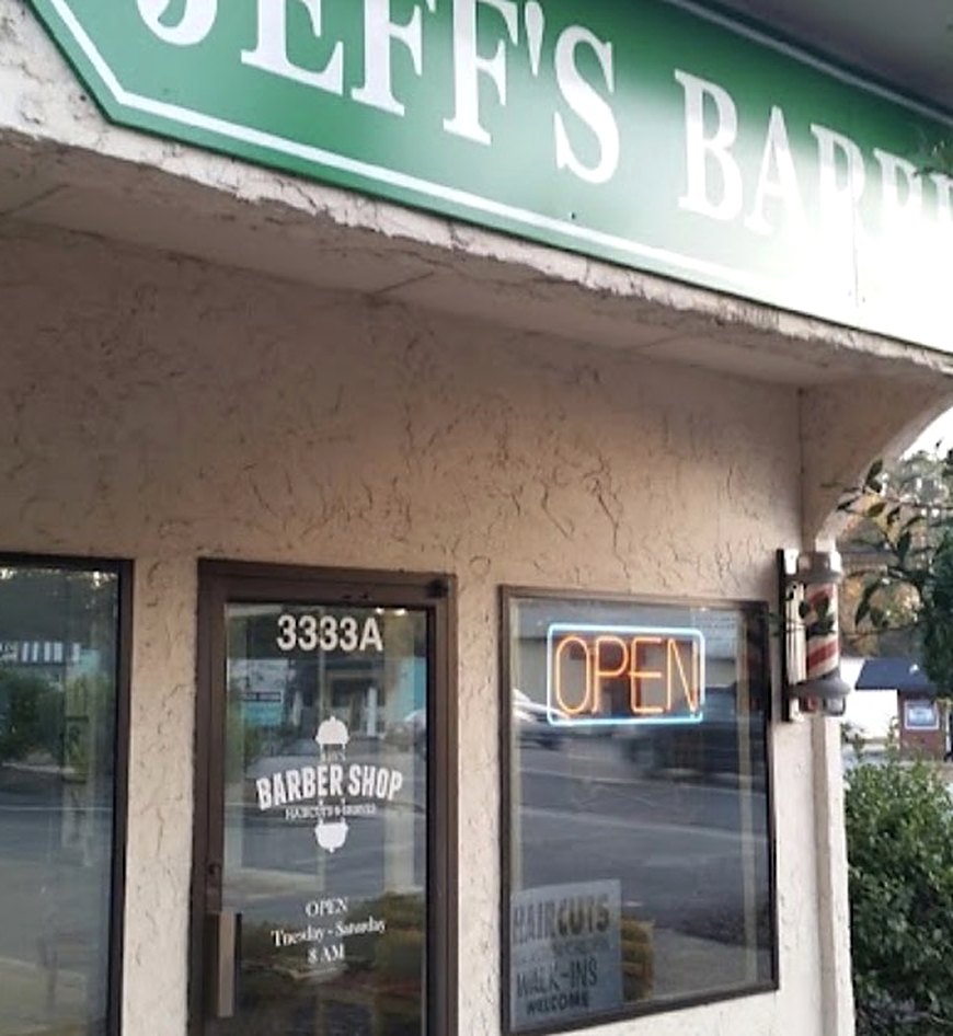 The front of Jeff's Barber Shop: green sign, door marked 3333A, an open sign and a barber pole.